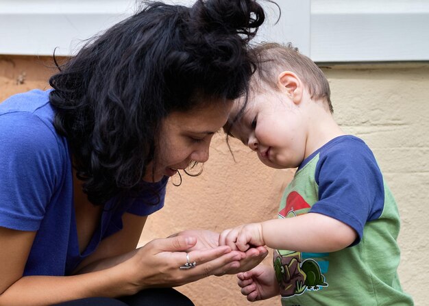 Foto un niño pequeño y lindo está jugando a las piedras con su madre en el porche trasero.