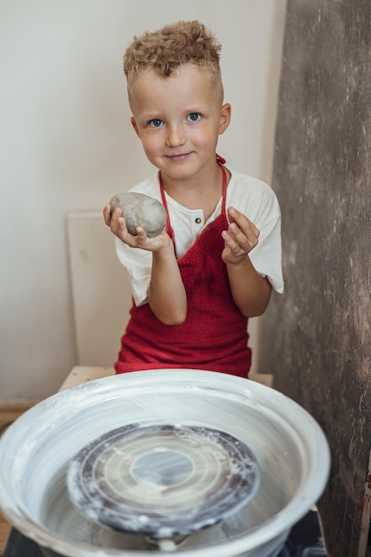 Un niño pequeño y lindo jugando con plastilina en un taller de cerámica, artesanía y arte en arcilla, actividades creativas para niños, educación en artes