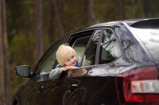 Niño pequeño lindo listo para un viaje o viaje. Coche familiar de viaje con niños.