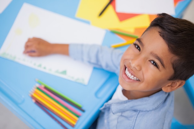 Niño pequeño lindo que dibuja en el escritorio