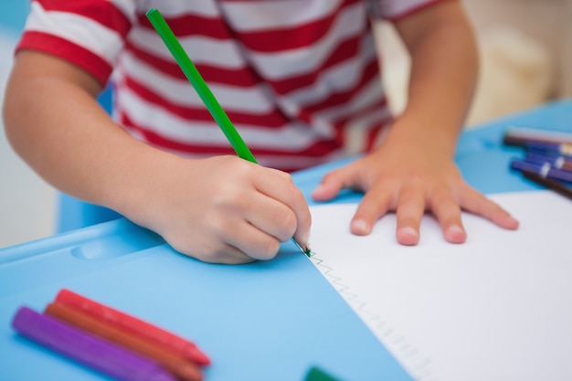 Niño pequeño lindo que dibuja en el escritorio