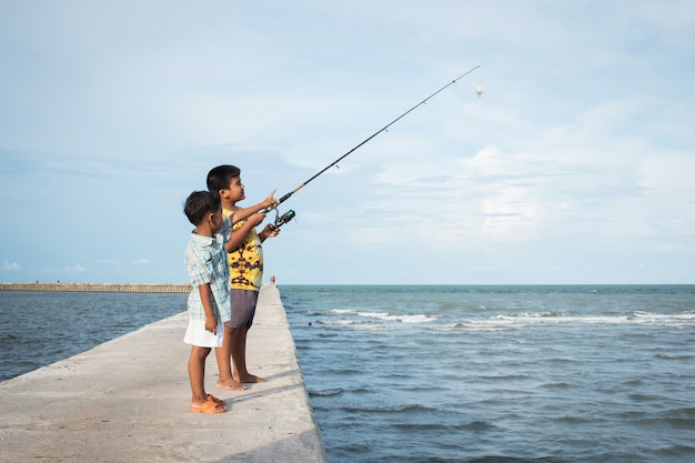 Niño pequeño lindo que pesca en el mar