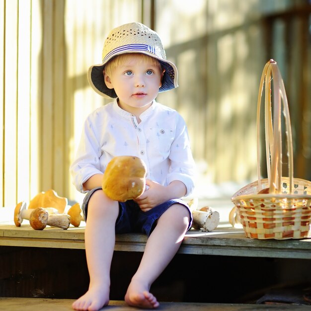 Niño pequeño lindo en seta de la cosecha del sombrero de paja