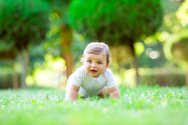 Niño pequeño lindo en traje blanco sentado en el césped