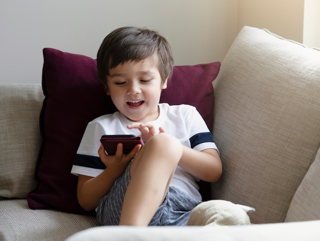 Niño pequeño lindo viendo dibujos animados en el teléfono móvil
