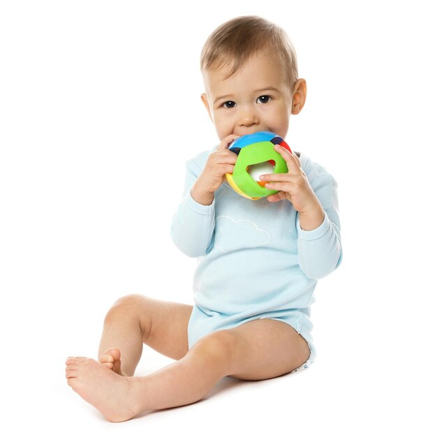 Niño pequeño en mameluco sentado y jugando con juguete de plástico