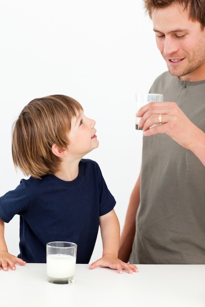 Niño pequeño mirando a su padre bebiendo leche