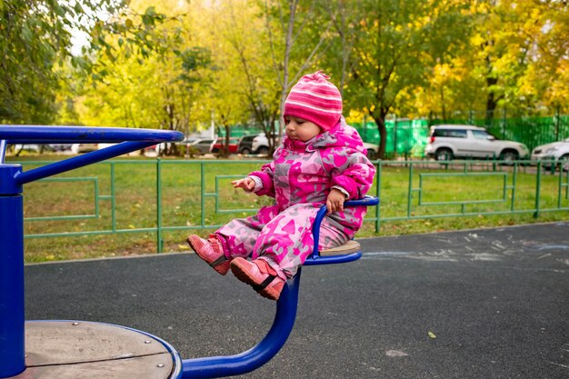 niño pequeño con un mono de invierno cálido juega en el patio de recreo. enfoque suave