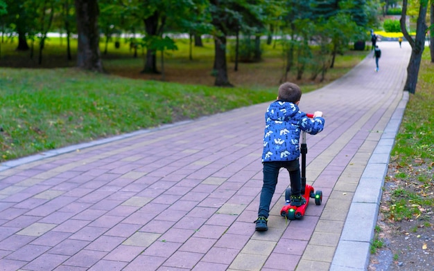 Un niño pequeño monta en su scooter