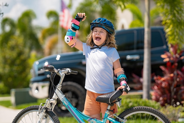 Niño pequeño montando una bicicleta en el parque de verano niños aprendiendo a conducir una bicicleta en una calzada fuera de k
