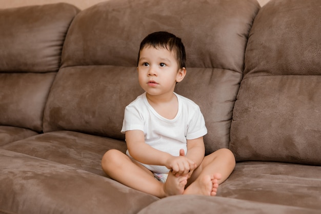 Niño pequeño Morena juega en casa en el sofá