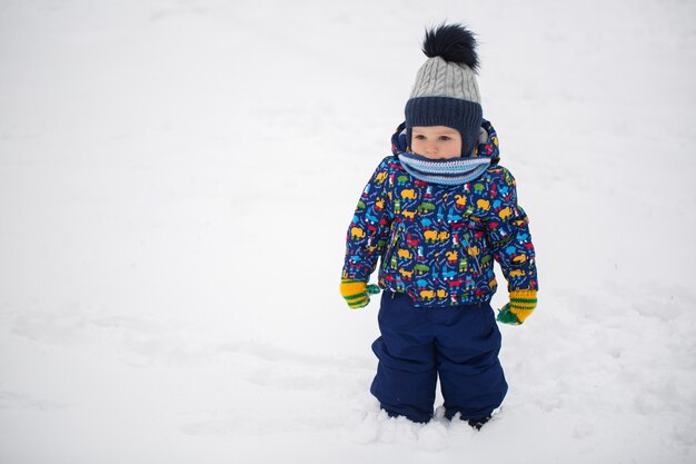 Niño pequeño en la nieve del invierno.