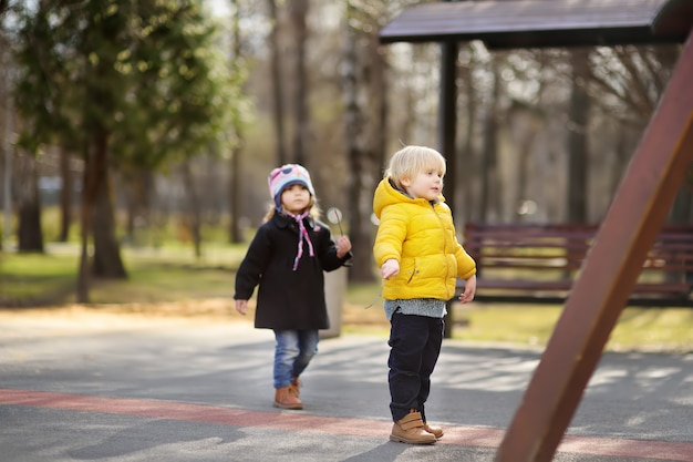 Niño pequeño y niña divirtiéndose en el patio al aire libre en la primavera o el día de otoño