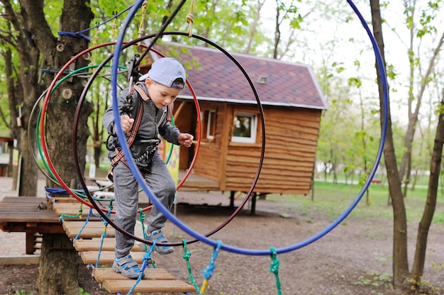 Un niño pequeño niño en edad preescolar es un obstáculo en un equipo de alpinismo de seguridad High rope Park