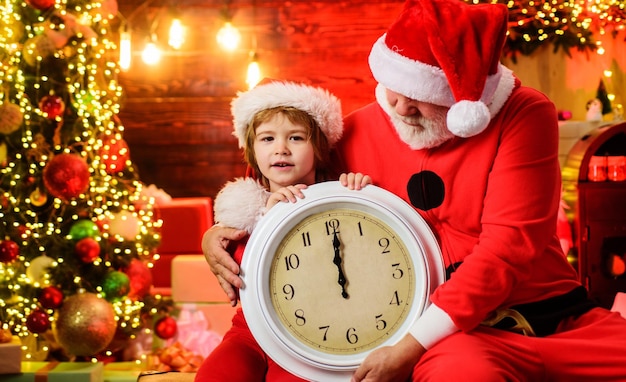Niño pequeño niño y santa claus con reloj viejo esperando navidad año nuevo medianoche