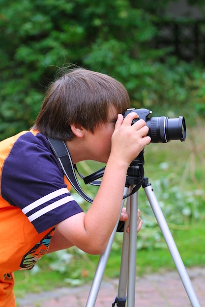 Niño pequeño niño tomando fotos con cámara de trípode