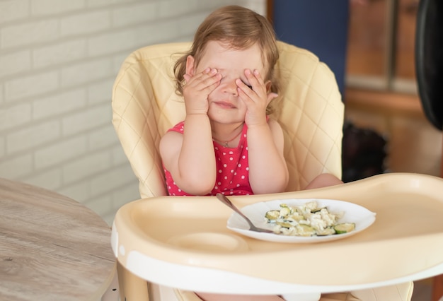 Un niño pequeño no quiere comer lasaña con verduras y es travieso
