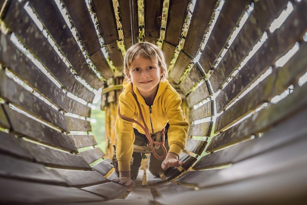 Niño pequeño en un parque de cuerdas Recreación física activa del niño al aire libre en el parque Entrenamiento para niños