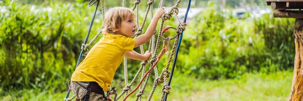 Niño pequeño en un parque de cuerdas recreación física activa del niño al aire libre en el parque