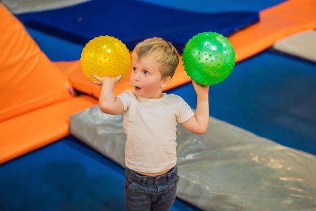 Niño pequeño con una pelota en trampolines