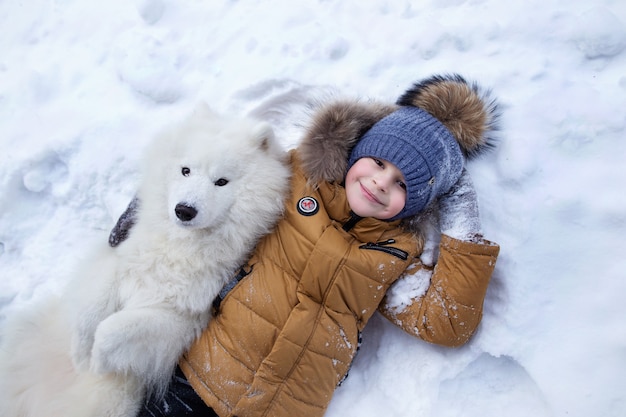 Foto niño pequeño con un perro en la nieve