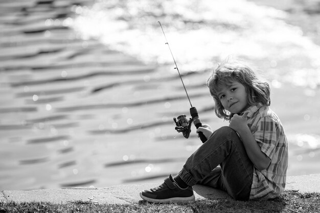 Niño pequeño pescador en el río niño pesca verano actividad de ocio al aire libre niño pequeño pesca con caña en el río