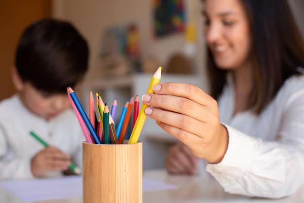 Niño pequeño preescolar dibujando con lápices de colores con madre o profesora. Centrarse en los lápices. Educación en el hogar. Comunidad de aprendizaje. escuela Montessori.