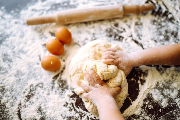 Niño pequeño preparando masa para hornear. Manos pequeñas amasando masa y masa enrollada