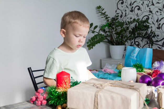 Un niño pequeño en previsión de Navidad y Año Nuevo jugando con adornos navideños esperando un milagro