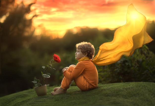 Foto un niño pequeño, un príncipe, se sienta con una flor rosa al atardecer