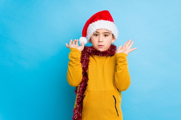 Niño pequeño que celebra el día de Navidad que lleva un sombrero de santa aislado sorprendido y conmocionado.