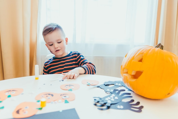 Niño pequeño que hace la cabeza de las calabazas del papel