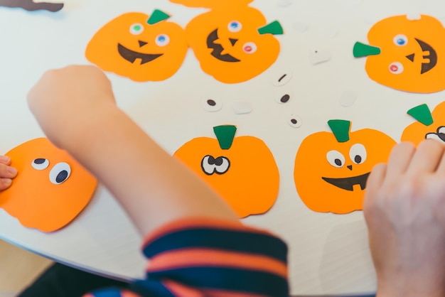 Niño pequeño que hace la cabeza de las calabazas del papel