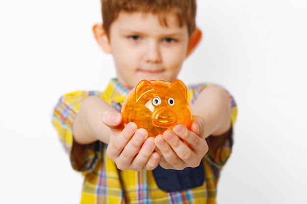 Niño pequeño que lleva a cabo el piggybank en manos.