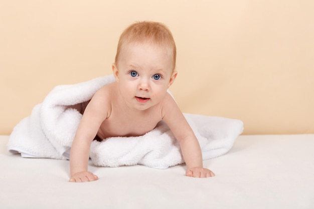 Niño pequeño que se relaja en el dormitorio después del baño o la ducha recién nacido