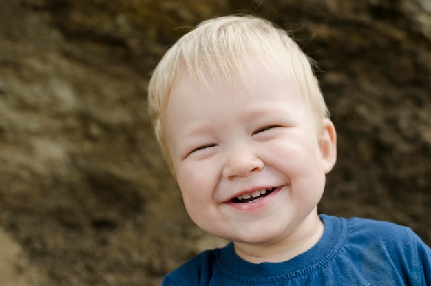 Un niño pequeño que se ríe es un retrato de primer plano rubio al aire libre Felicidad emoción