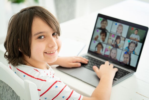 Foto niño pequeño que tiene una clase de aprendizaje a distancia en la escuela en línea en casa