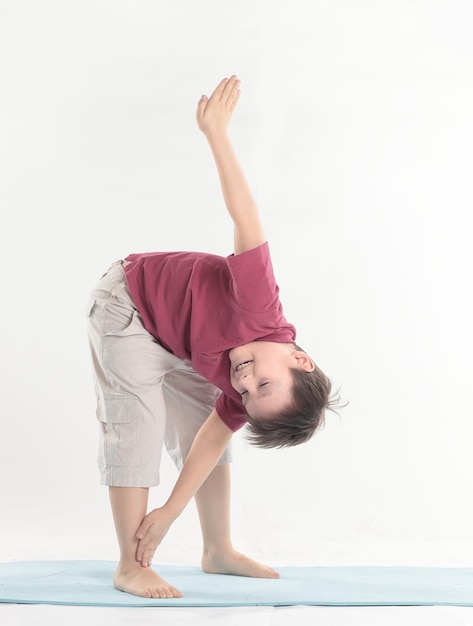 El niño pequeño realiza un ejercicio para estirar los músculos aislados en blanco