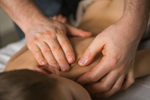 Niño pequeño se relaja con un masaje terapéutico. Fisioterapeuta que trabaja con el paciente en la clínica a la espalda de un niño