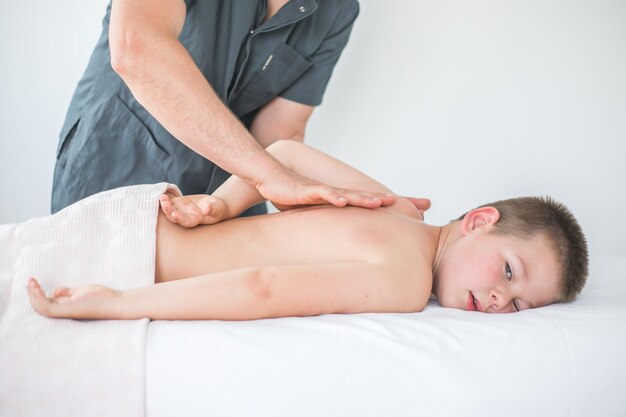 Niño pequeño se relaja con un masaje terapéutico Fisioterapeuta que trabaja con un paciente en la clínica para tratar la espalda de un niño