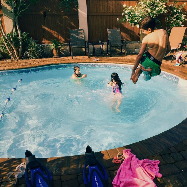 Foto niño pequeño saltando a la piscina