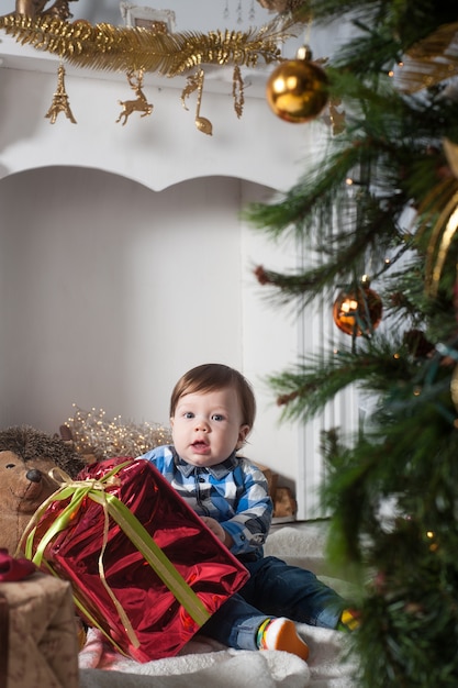 niño pequeño sentado cerca del árbol de navidad en casa