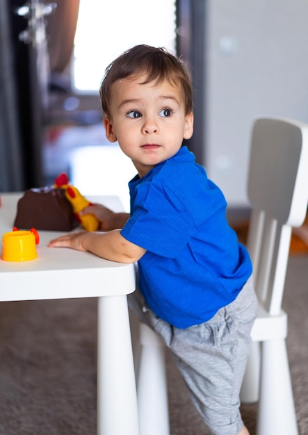 Foto un niño pequeño sentado en una mesa con un coche de juguete