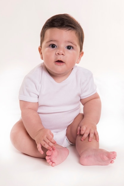 Niño pequeño sentado y mirando a cámara. Bebé brasileño.