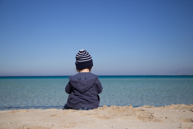 Niño pequeño, sentado, en, un, playa, vista trasera