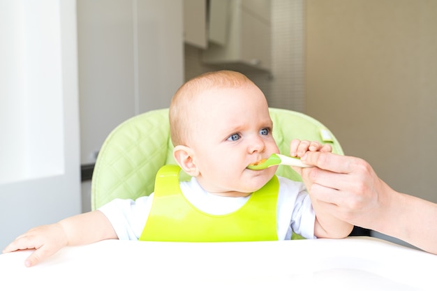 niño pequeño sentado en una silla alta y come