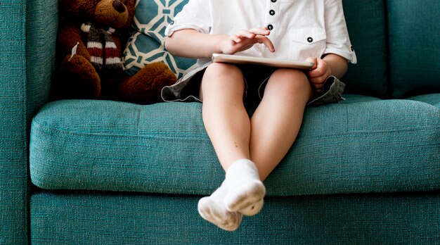 Niño pequeño sentado en un sofá con tableta digital