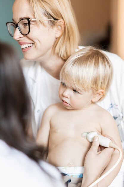 Foto niño pequeño siendo examinado por ultrasonido cardíaco por un cardiólogo como parte de