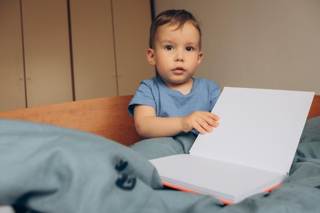 Un niño pequeño se sienta en la cama con un libro titulado 'la palabra amor'.