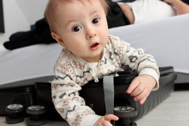 Un niño pequeño se sienta en una maleta y juega.